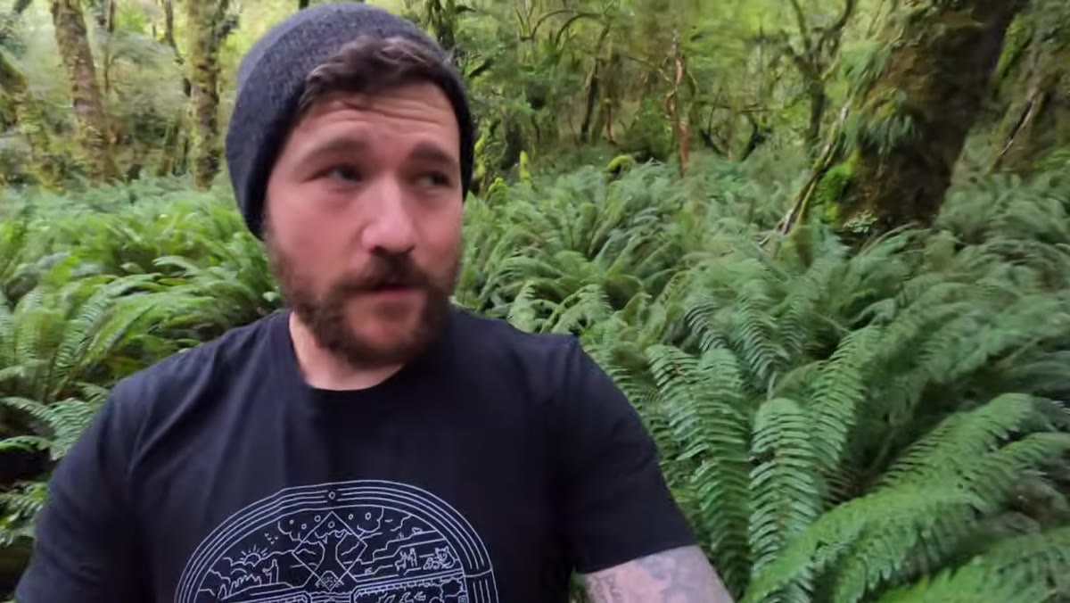 Patino walking through misty, rain-soaked Fiordland forest