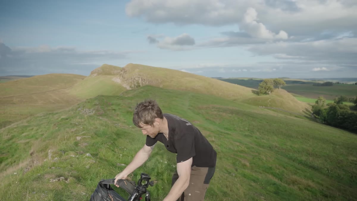 Heaton composing a shot of two distant trees on a hillside with dramatic sky