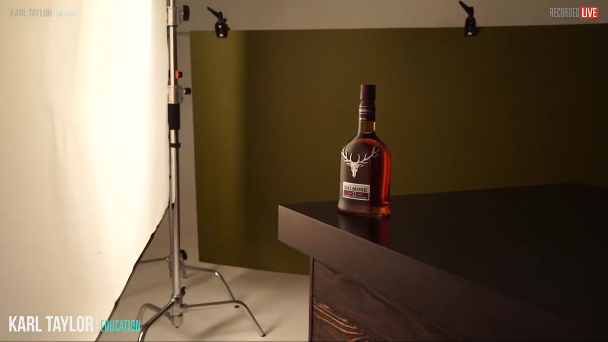 Assistant moving softbox further from scrim, light changing on bottle