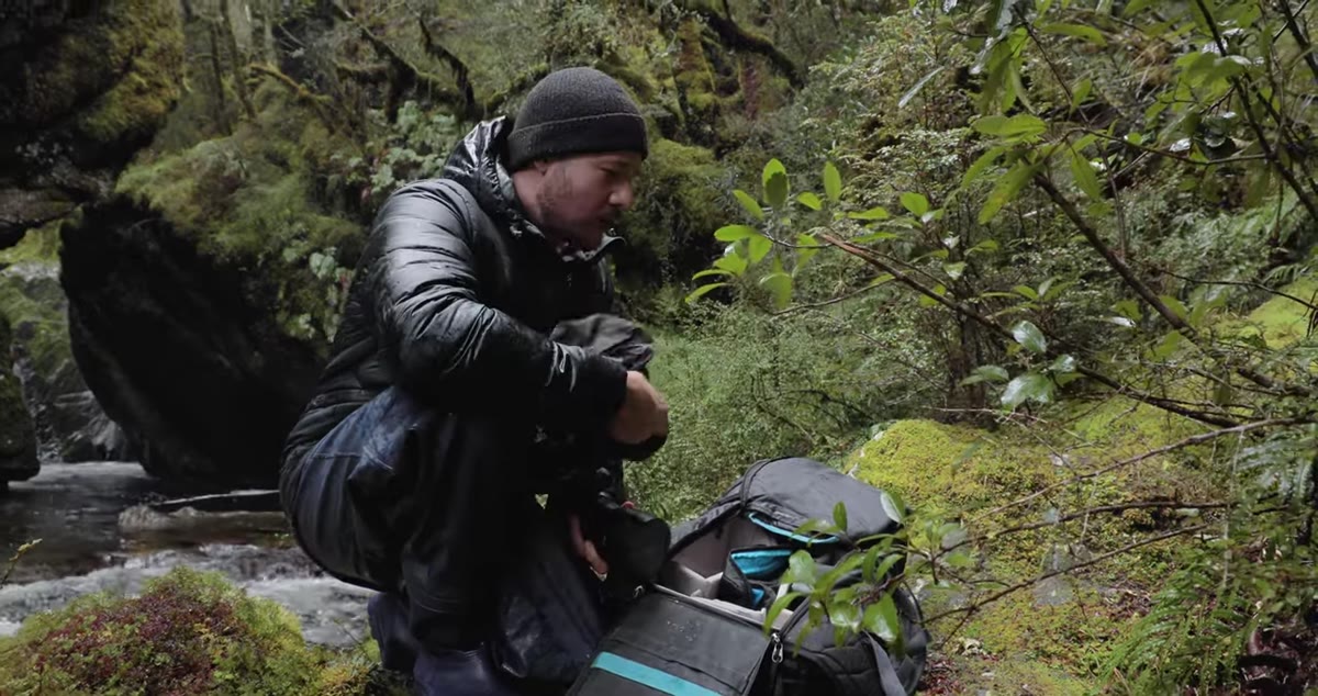 Photographer covering camera body with a microfiber towel in rain