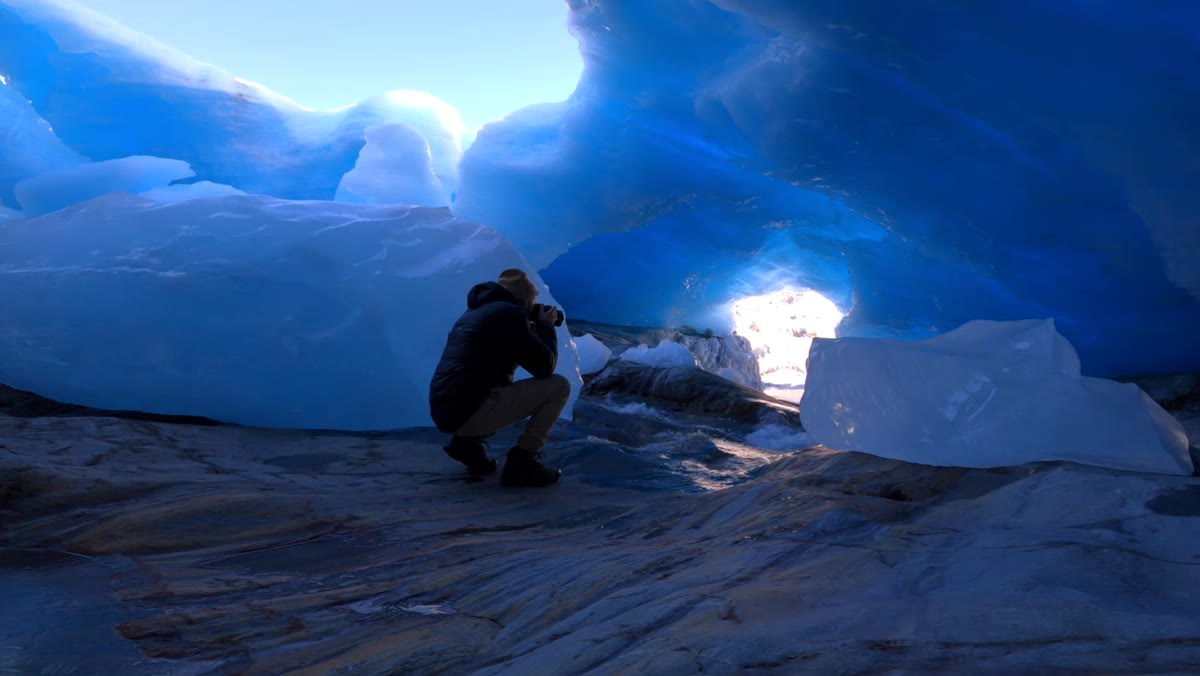 Water flowing inside ice cave with blue light filtering through