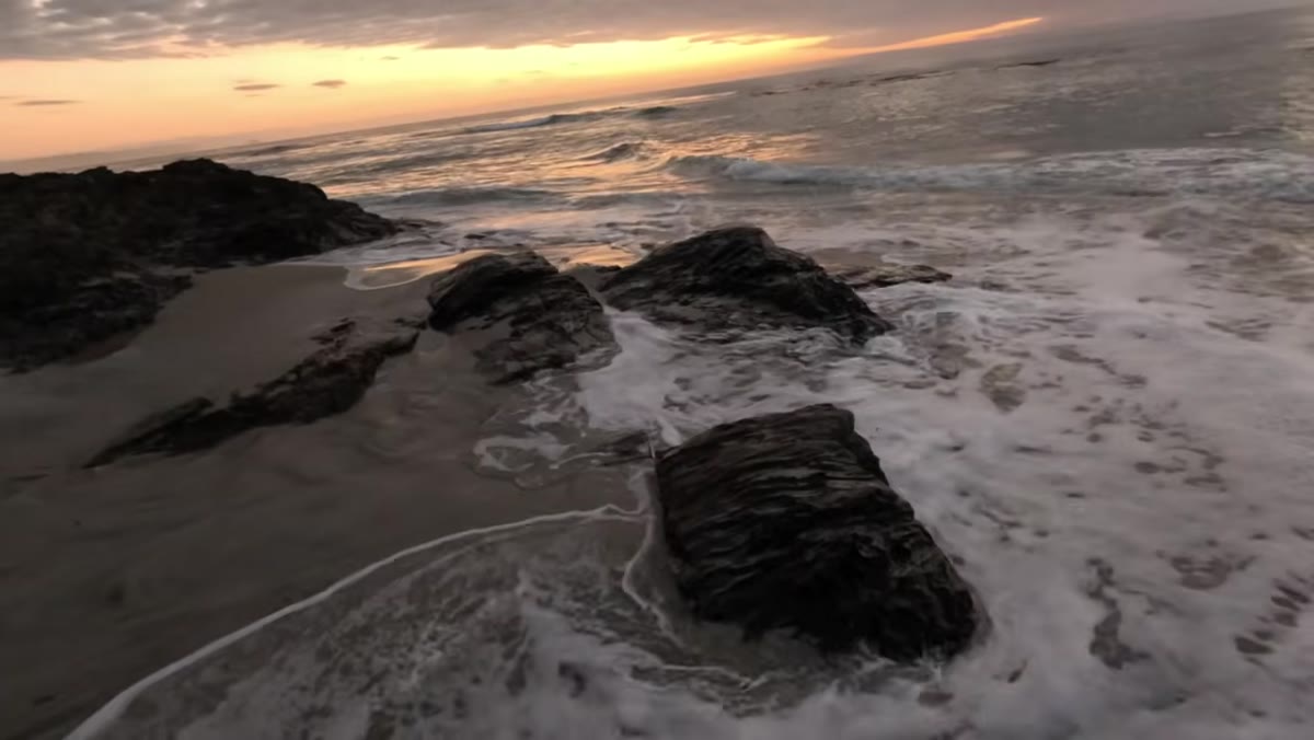 Water pulling back from rocks creating smooth trailing motion