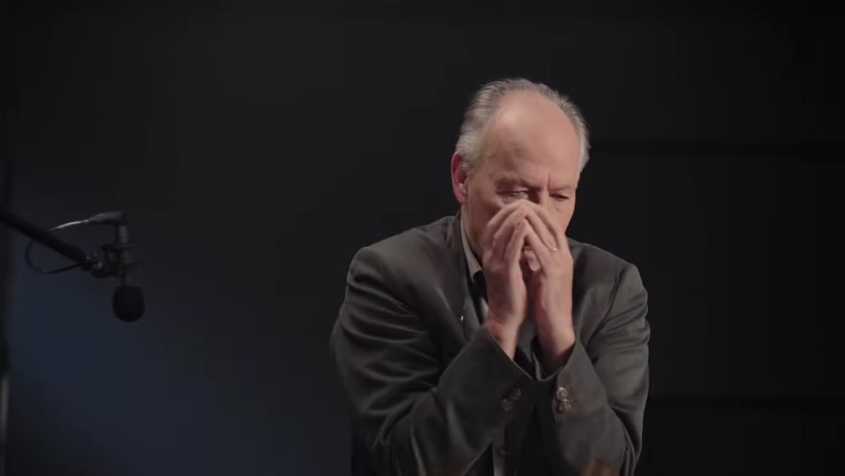 Tucker describing the book The Peregrine, gesturing thoughtfully