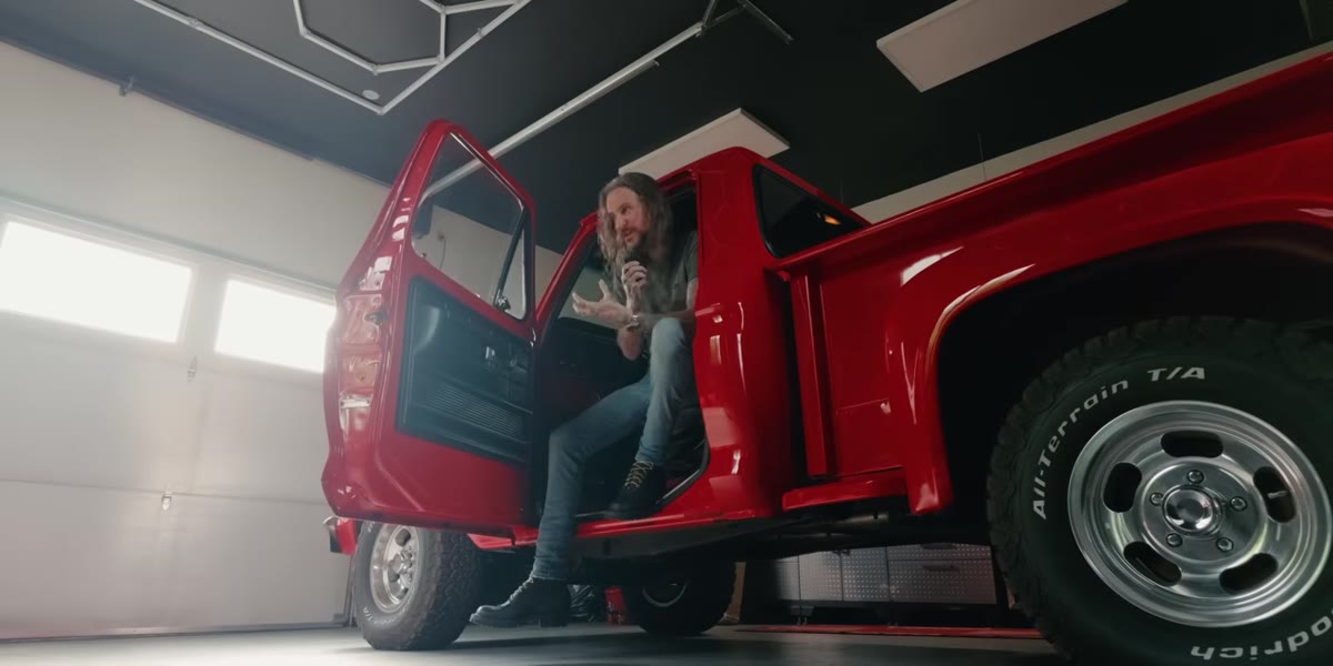 McKinnon gesturing toward vintage truck in parking lot